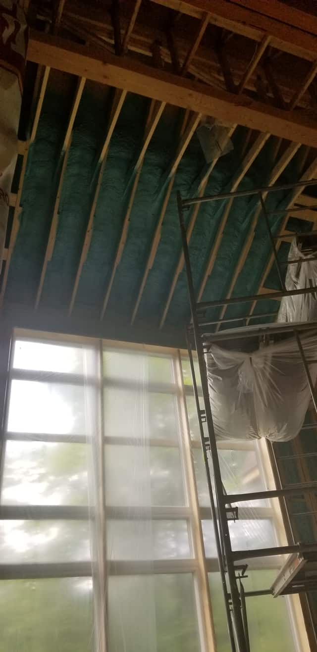 Spray foam applied between roof rafters, sealing the underside of the roof deck