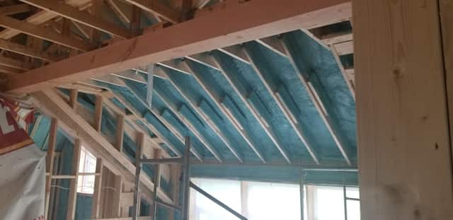 Spray foam applied between roof rafters, sealing the underside of the roof deck