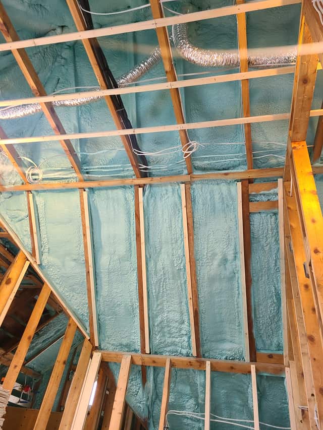 Spray foam applied between roof rafters, sealing the underside of the roof deck
