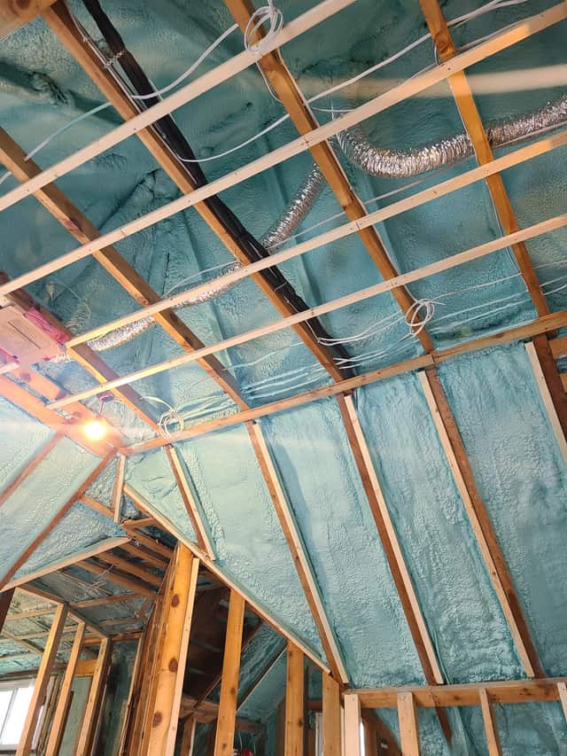 Spray foam applied between roof rafters, sealing the underside of the roof deck