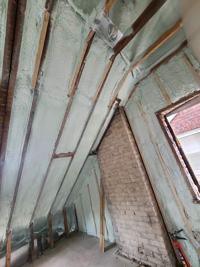 Spray foam applied between roof rafters, sealing the underside of the roof deck