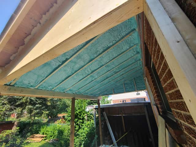 Spray foam applied between roof rafters, sealing the underside of the roof deck