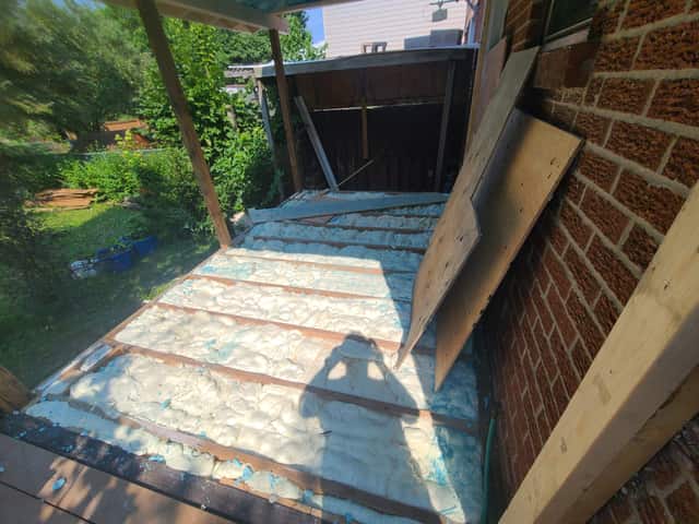 Spray foam applied between roof rafters, sealing the underside of the roof deck