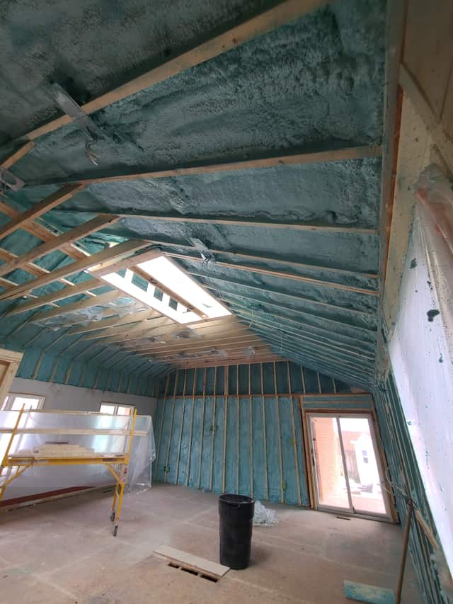 Spray foam applied between roof rafters, sealing the underside of the roof deck