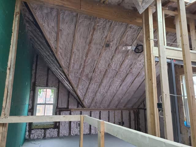 Spray foam applied between roof rafters, sealing the underside of the roof deck