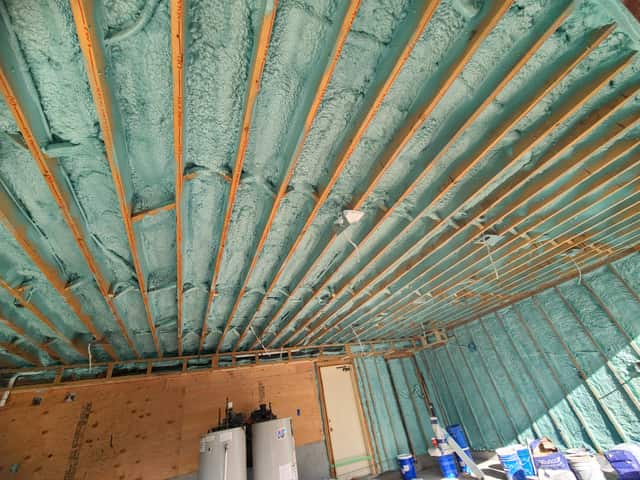 Spray foam applied between roof rafters, sealing the underside of the roof deck