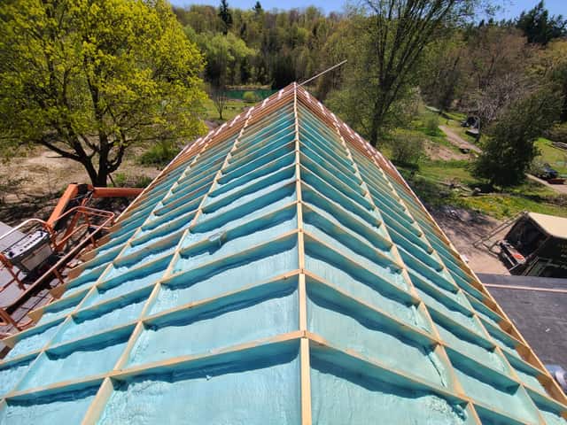 Spray foam applied between roof rafters, sealing the underside of the roof deck