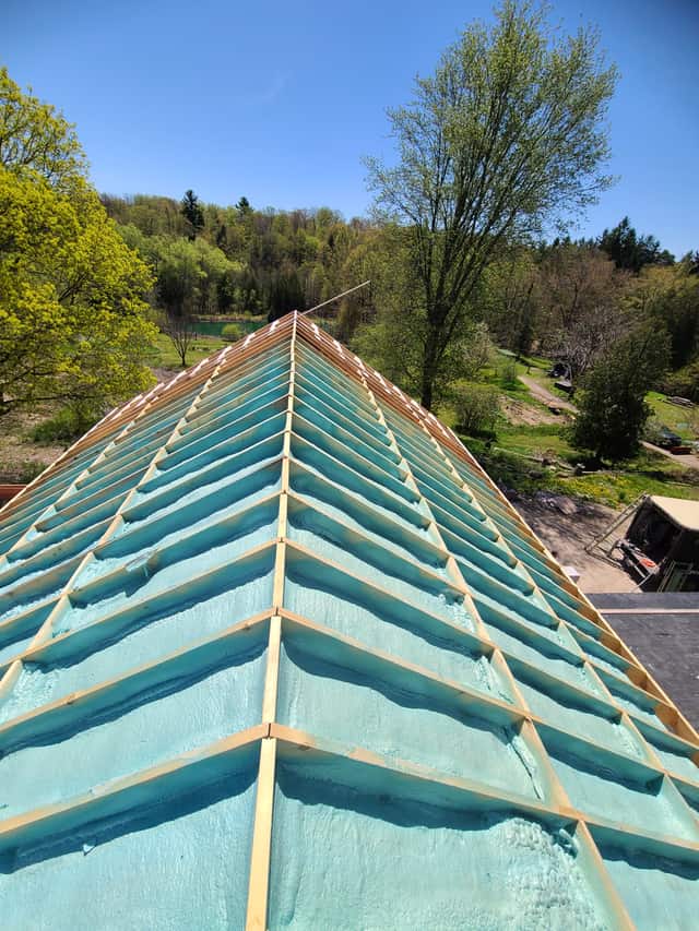 Spray foam applied between roof rafters, sealing the underside of the roof deck