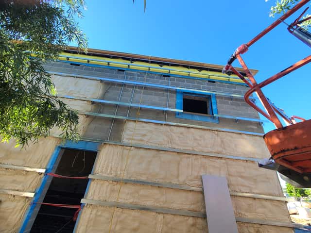 The exterior wall of a commercial building being insulated with spray foam