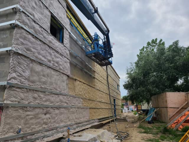 The exterior wall of a commercial building being insulated with spray foam