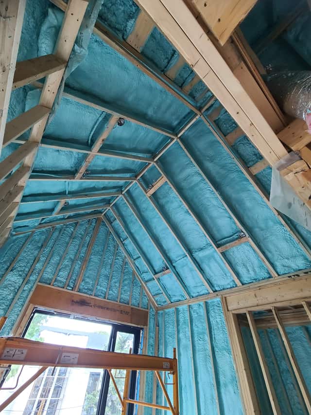 Spray foam applied between roof rafters, sealing the underside of the roof deck